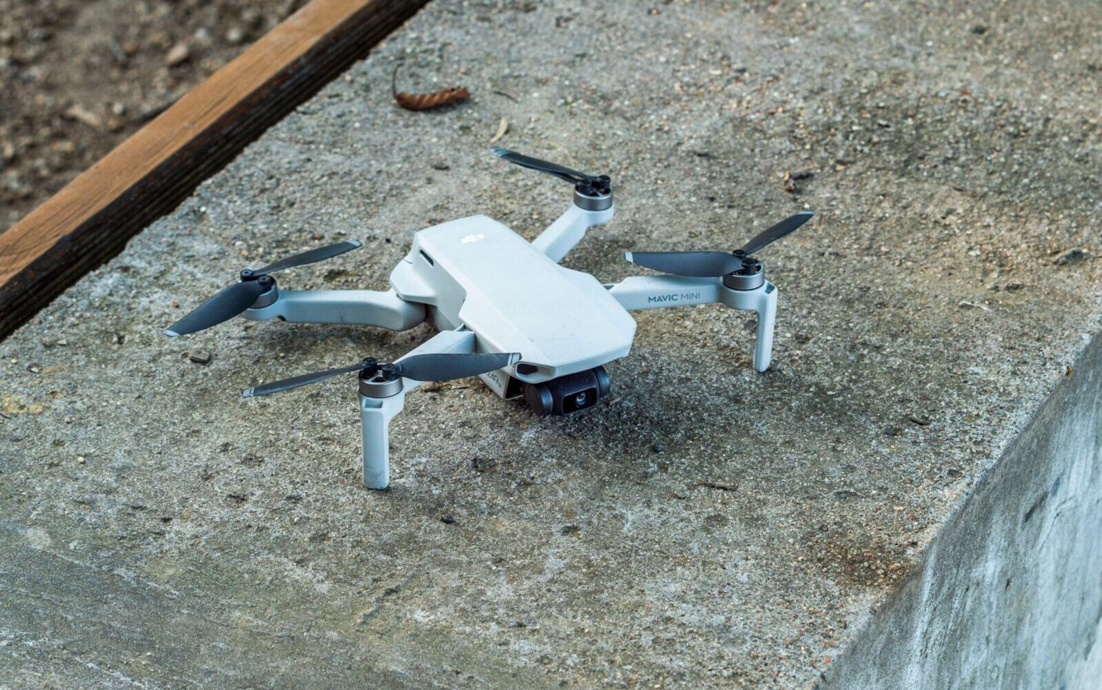 A close-up image of a compact drone resting on a concrete surface.