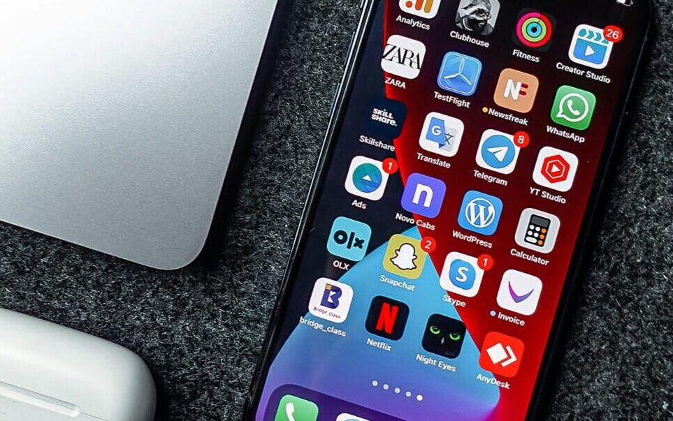 Flat lay of a smartphone, laptop, and earphones on a grey surface. Perfect for tech and gadget themes.